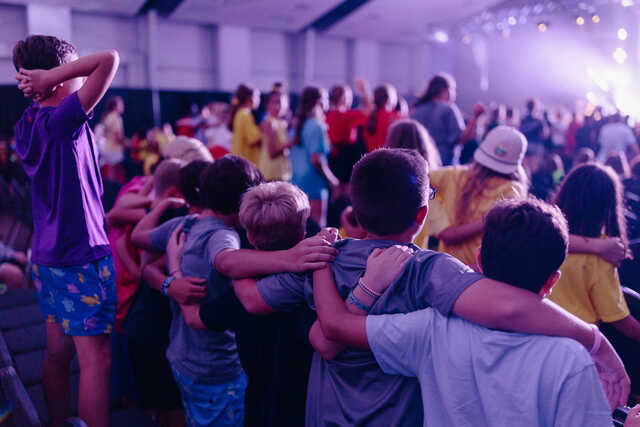 middle school boys with arms around each other at worship at frequency camp